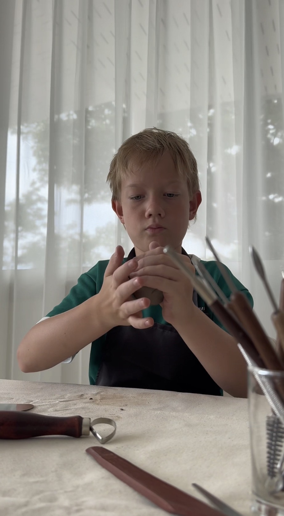 Child shaping clay during a ceramics workshop at Atelier 179